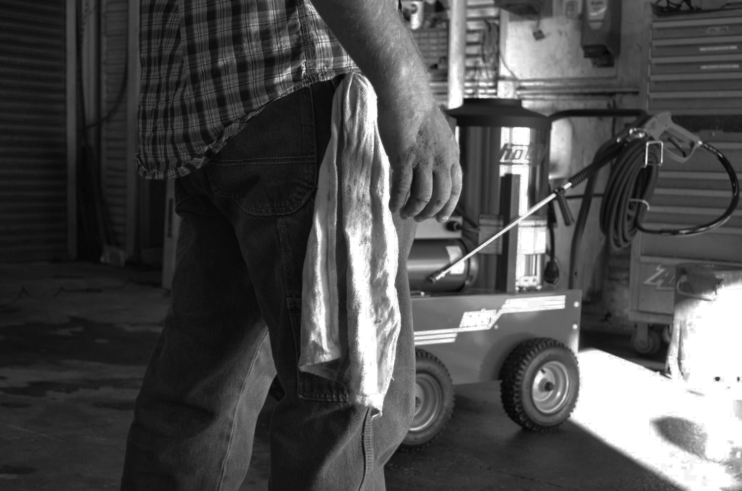 black and white image of man in a garage with a hotsy powerwasher
